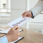 Employee giving resignation letter to boss in office, closeup